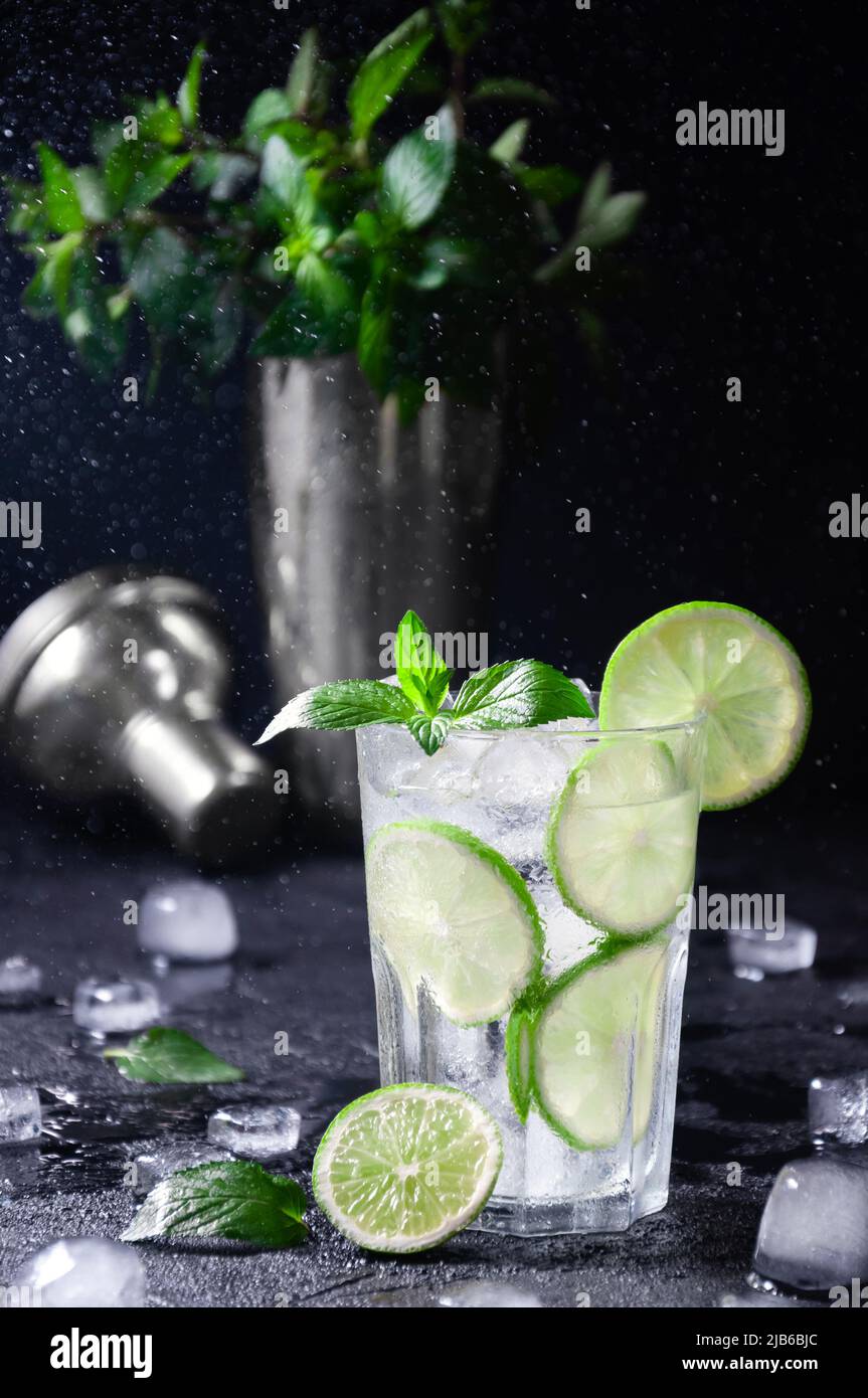 Cocktail Mojito or Lemonade with Lime, Mint and Ice in Freeze Motion, Drops in Liquid Splash on Dark Background. Concept Fresh Summer Drinks Stock Photo