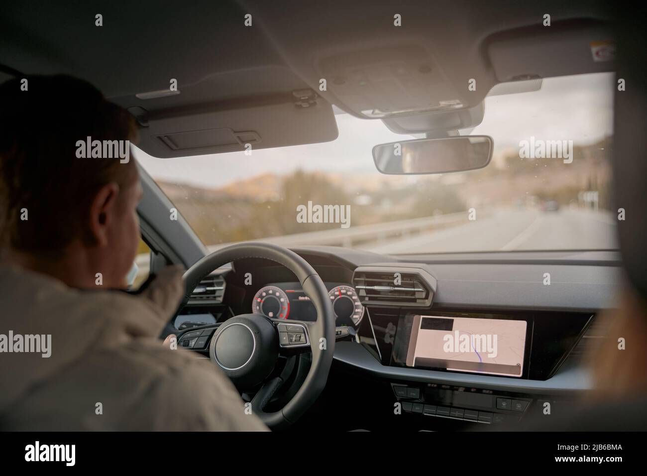 Rear of man driver driving a car, shot from inside the car, traveling in automobile Stock Photo