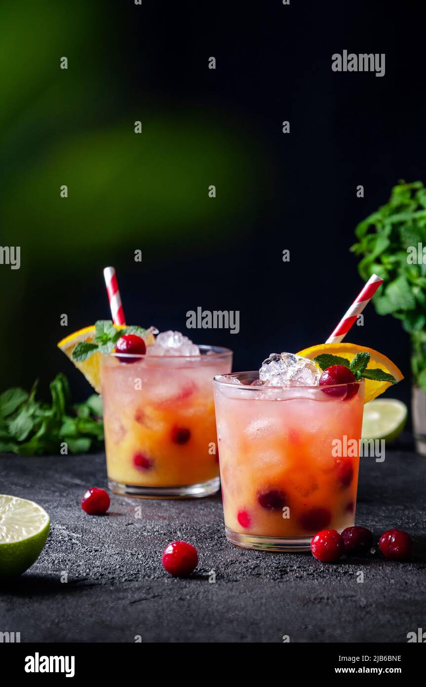 Cocktail with Rum or Vodka, Soda, Cranberry, Orange Juice, Lime and Mint in the Glass on Dark Grey Background Stock Photo