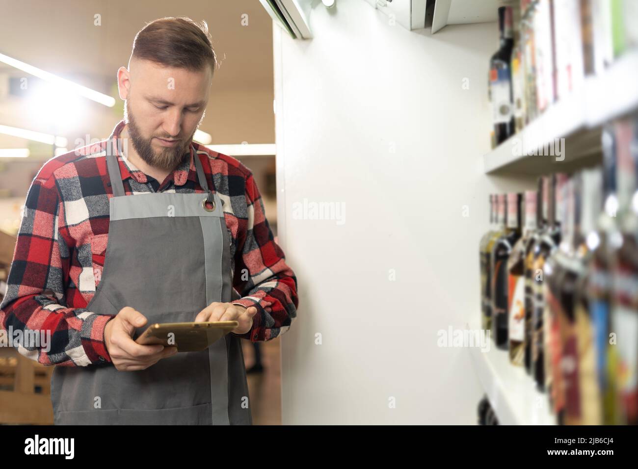 supermarket worker using digital tablet, grocery store employee orders groceries online, innovative technology and work Stock Photo
