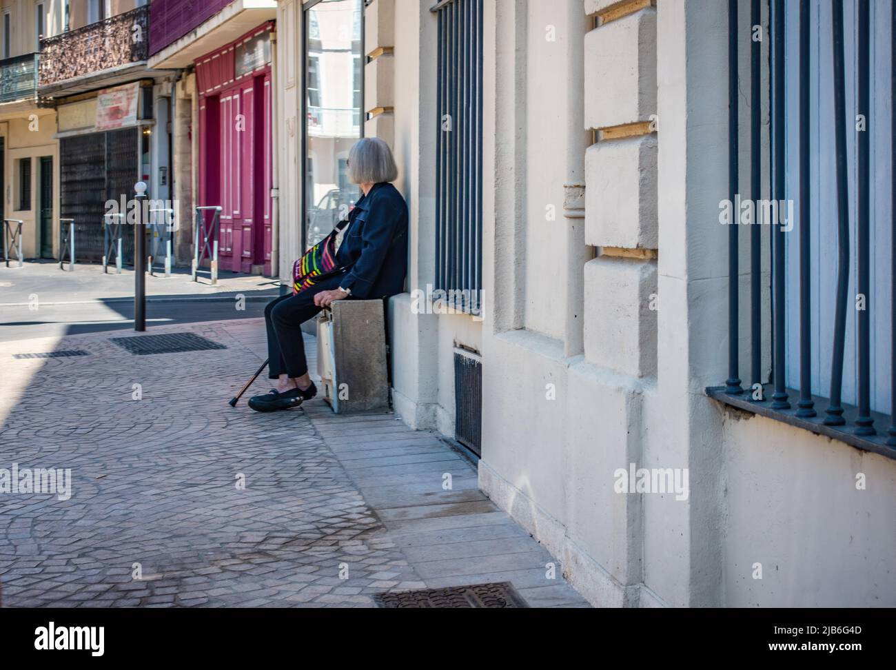 Elderly lady taking a break from walking in Beziers, France. Stock Photo