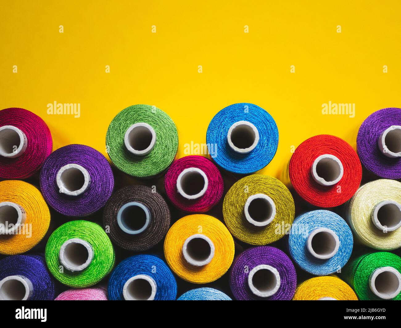 Multicolored threads for sewing and embroidery on the yellow background Stock Photo