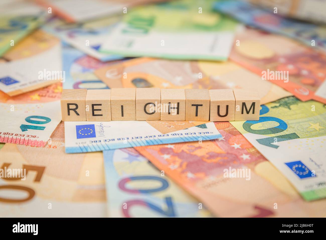 The word Reichtum - in German for rich - on banknotes Euro notes with wooden cube written text Stock Photo