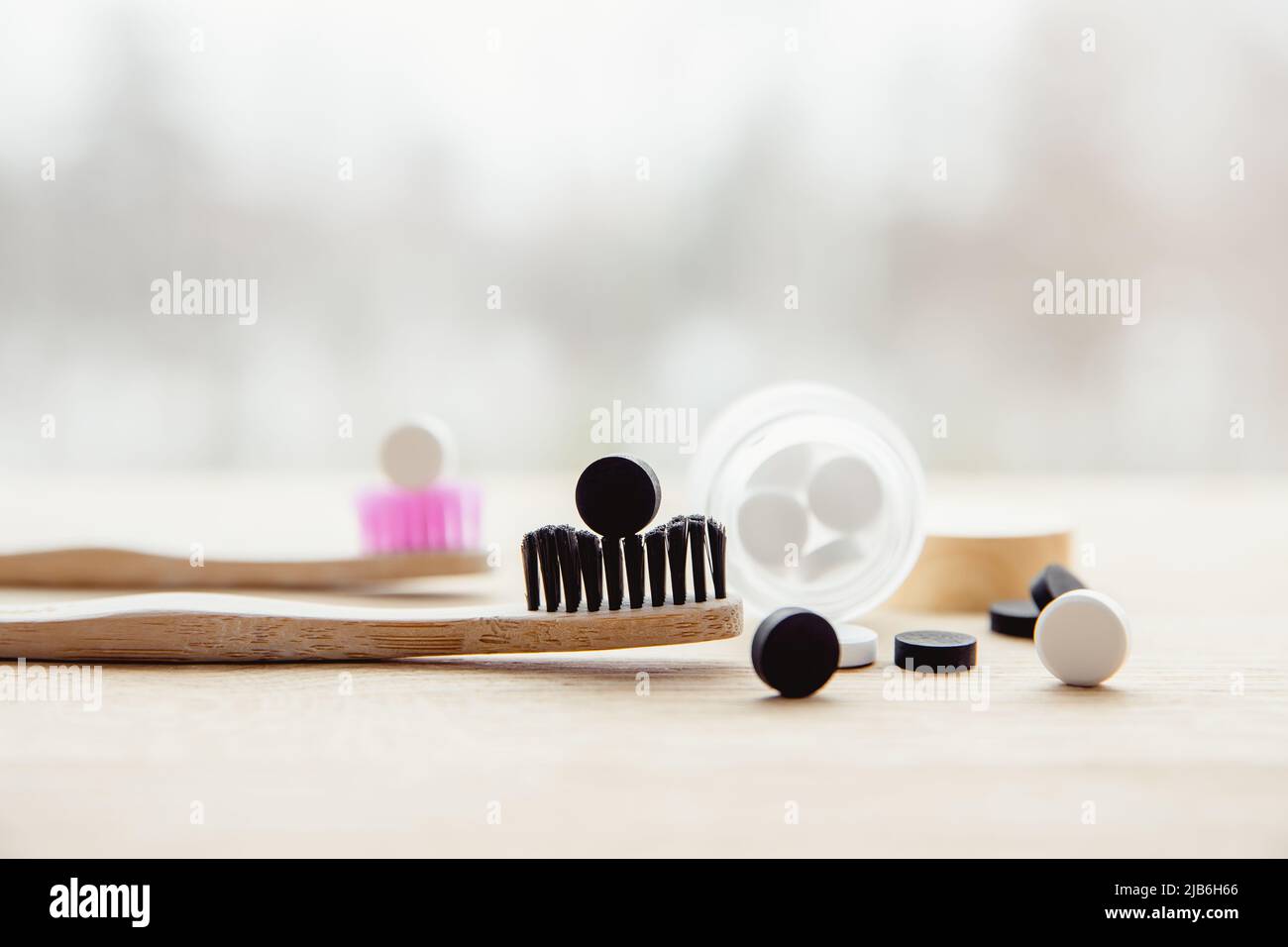 Side view of white toothpaste tablets with fluoride and black activated charcoal toothpaste tablets. Dental care concept. Copy space. Stock Photo