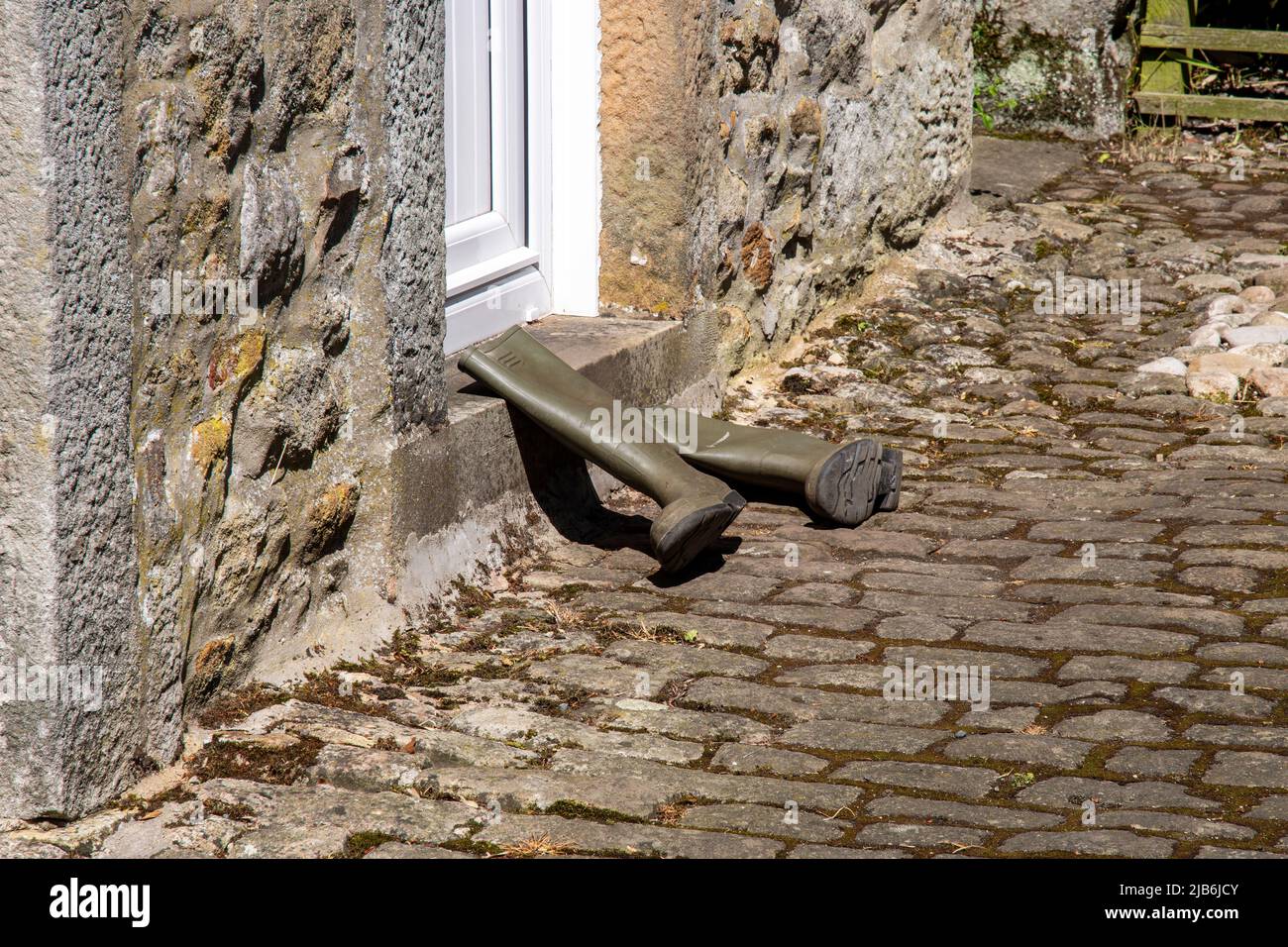 Green wellington boots lay beside a stone step on cobbles Stock Photo ...