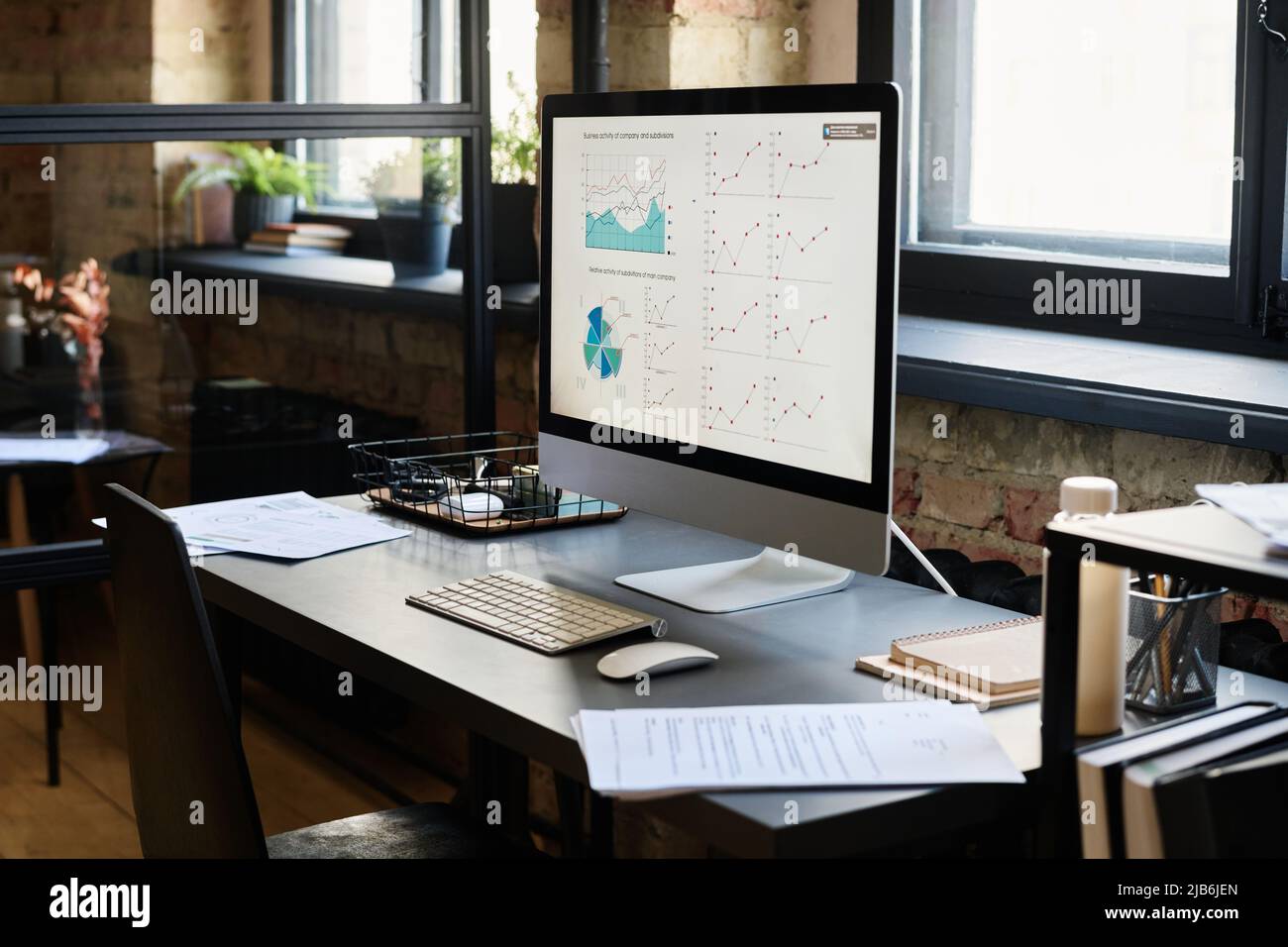 Image of desk of manager with computer on it with graphs on monitor at office Stock Photo