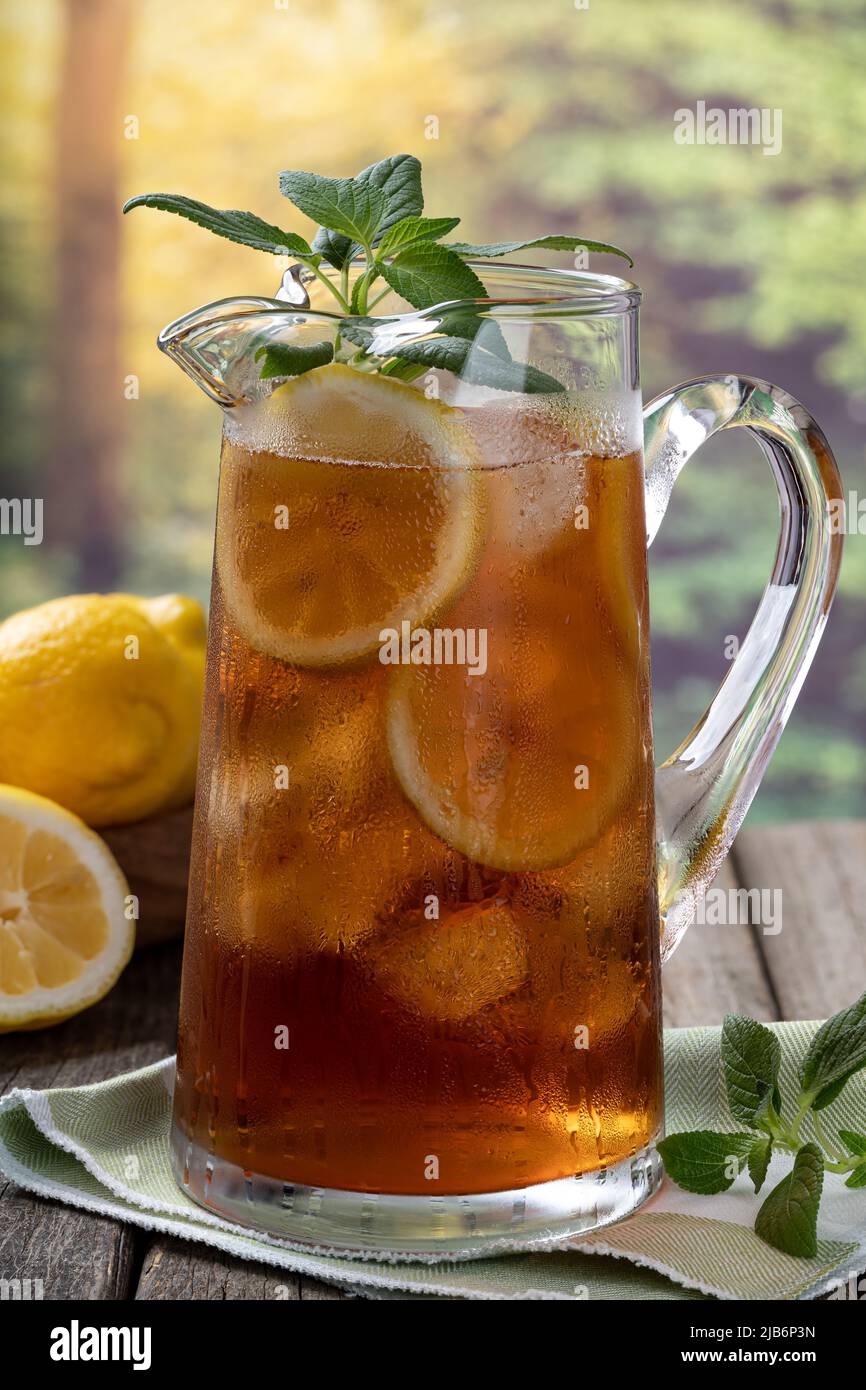 https://c8.alamy.com/comp/2JB6P3N/pitcher-of-iced-tea-with-ice-lemon-and-mint-on-old-wooden-table-with-rural-background-2JB6P3N.jpg