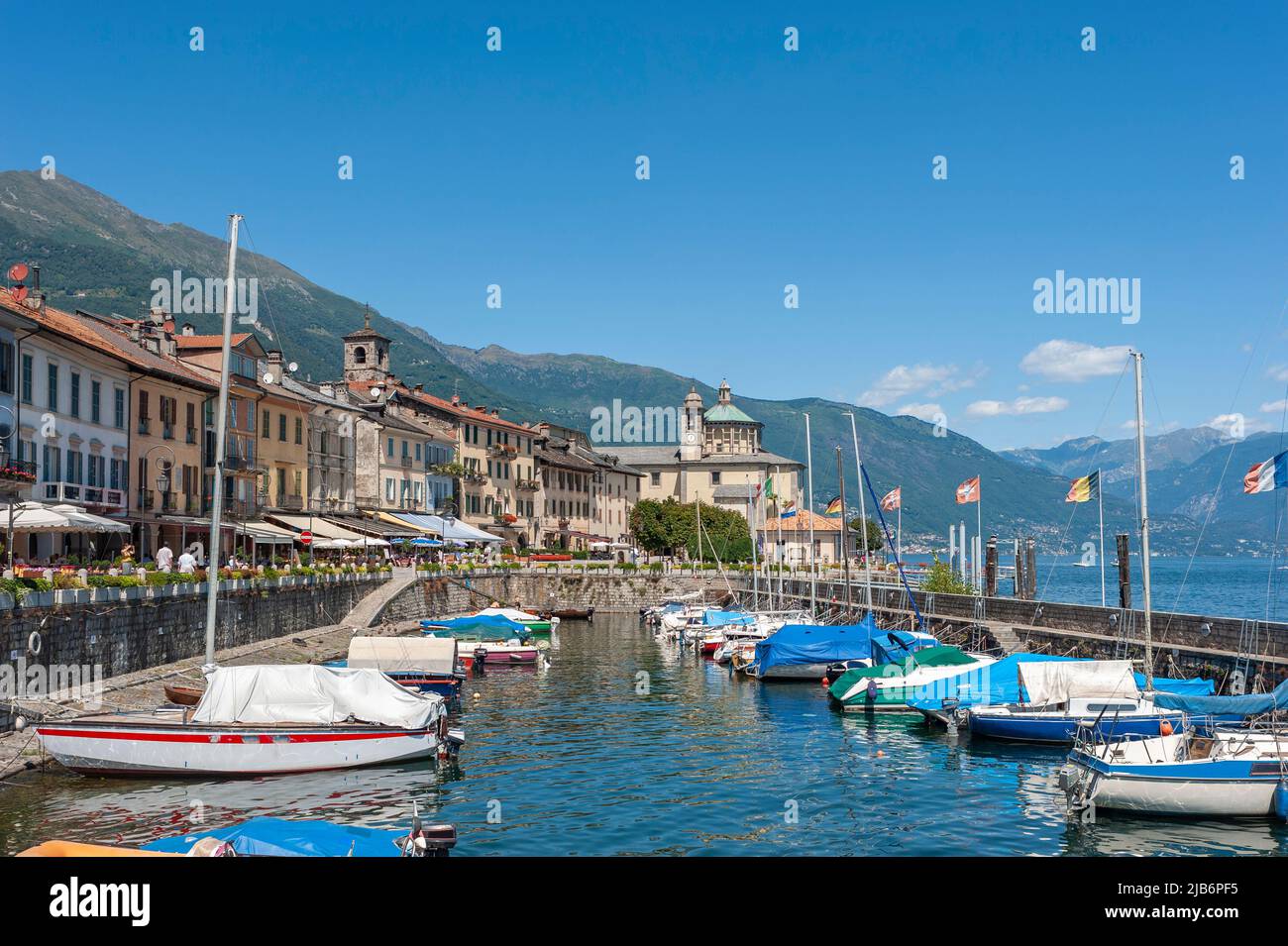 Port and historic house facades along the promenade of Lake Maggiore. In the background the Santuario della SS Pieta pilgrimage church, Cannobio, Pied Stock Photo