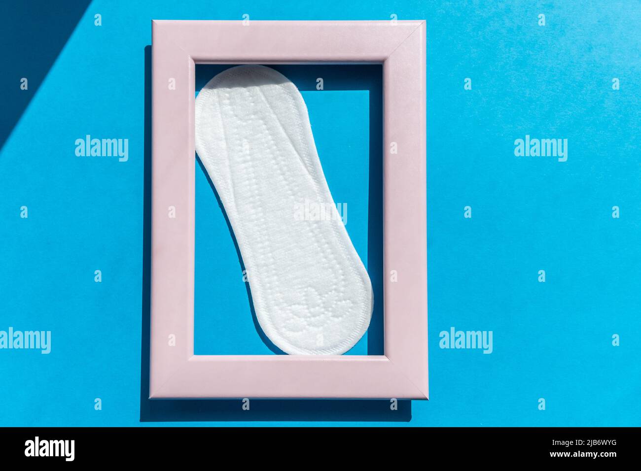 White sanitary pad in a pink photo frame on the blue background Stock Photo
