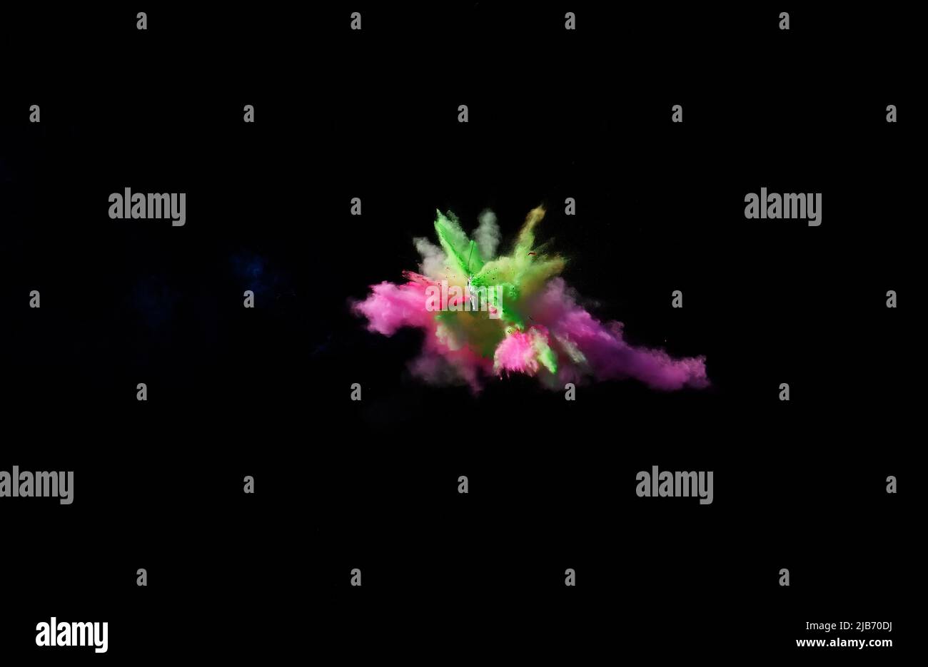 Various multicolored forms of powder paint explode in front of a black ...