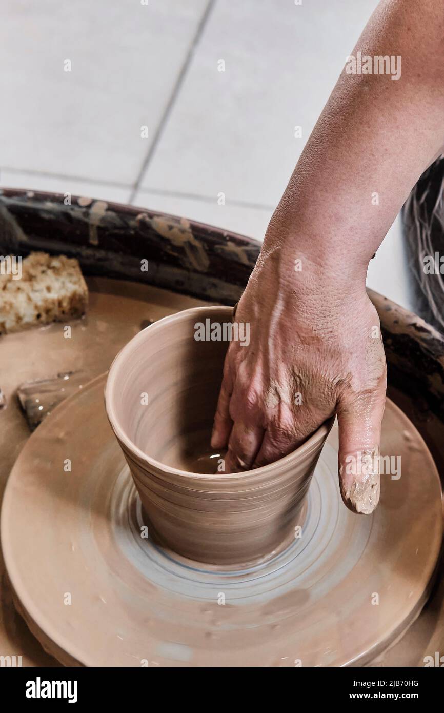 Hand of senior woman sculpting clay vase on potter's wheel Stock Photo