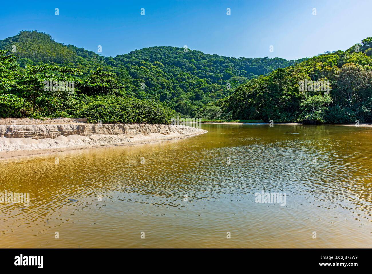 River waters flowing down between hills, sand and the forest to end up on the beach in Bertioga state of Sao Paulo. Stock Photo
