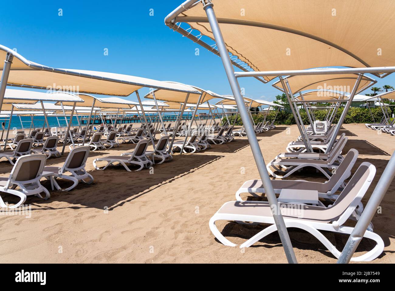 A rows of sunbeds at a deserted sandy beach in turkish resort. Sun