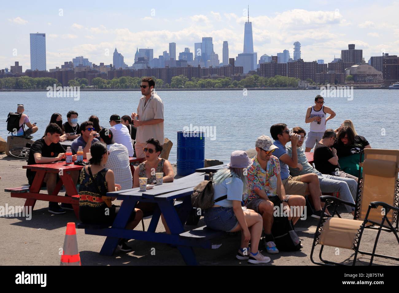 People relaxing by the East River at Greenpoint Terminal Market with Manhattan skyline in the background.Greenpoint.Brooklyn.New York City.USA Stock Photo