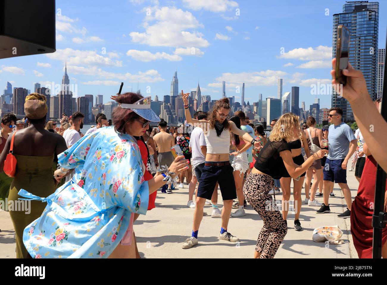 People dancing at the Hot Honey Sundays outdoor dance party in Greenpoint Terminal Market with East River and Manhattan skyline in the background.Greenpoint.Brooklyn.New York City.USA Stock Photo