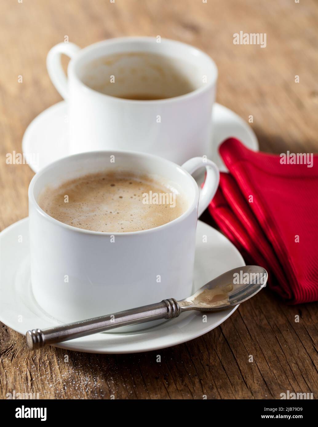 Two cups of espresso coffee on a wood tabletop with red napkin Stock