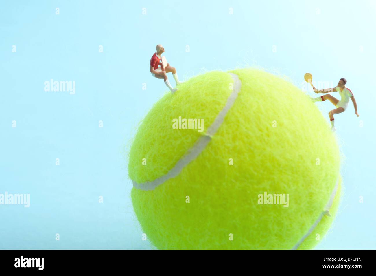 Two miniature tennis players on top of a ball competing in a match Stock Photo