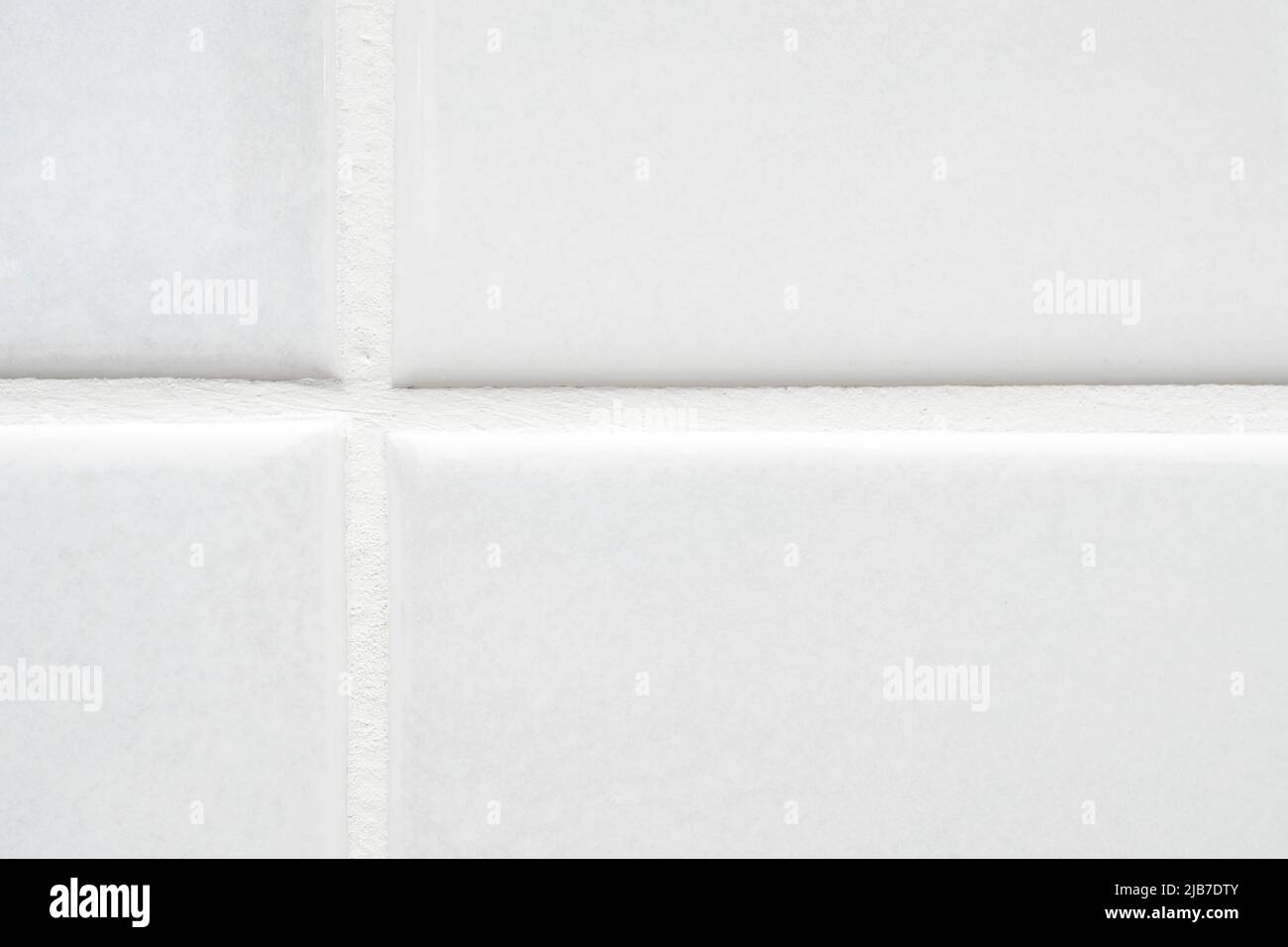 Closeup of part of white ceramic tile on the wall with clean new seam