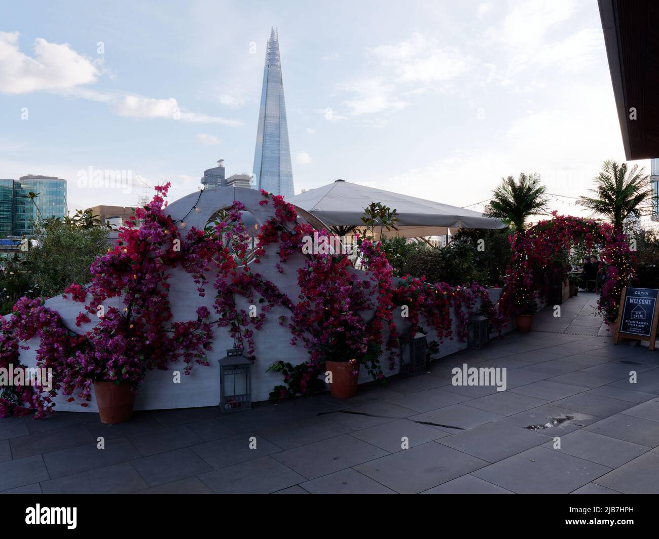 Artificial red and pink floral display at the Coppa club restaurant with The Shard skyscraper in the background. London. Stock Photo