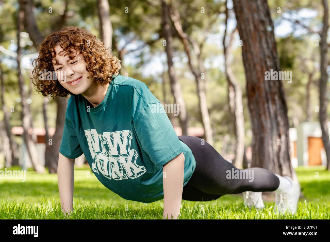Cute redhead woman wearing green sports bra and blue yoga pants