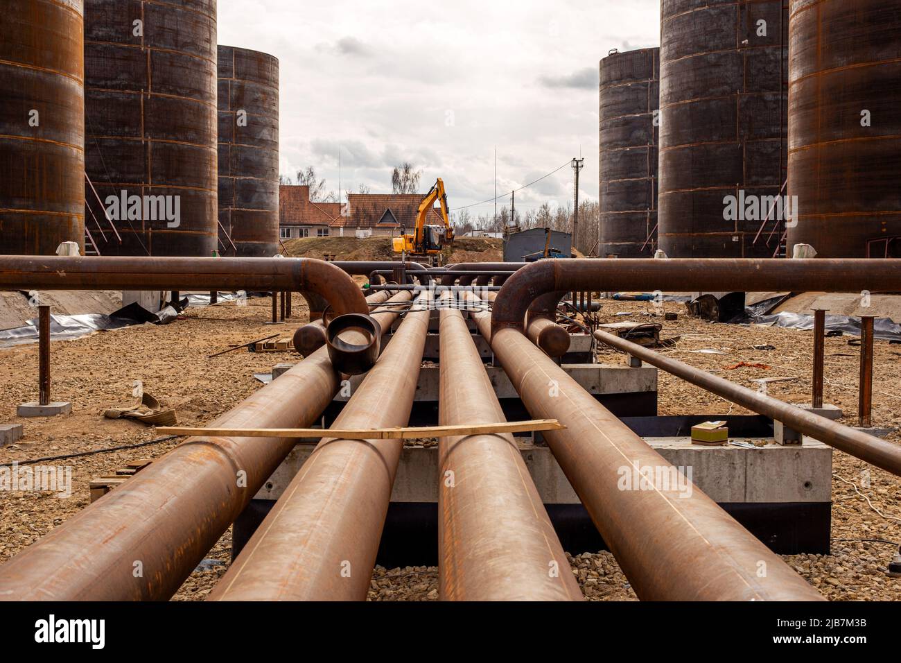 Oil refinery construction site with oil storage tanks in background