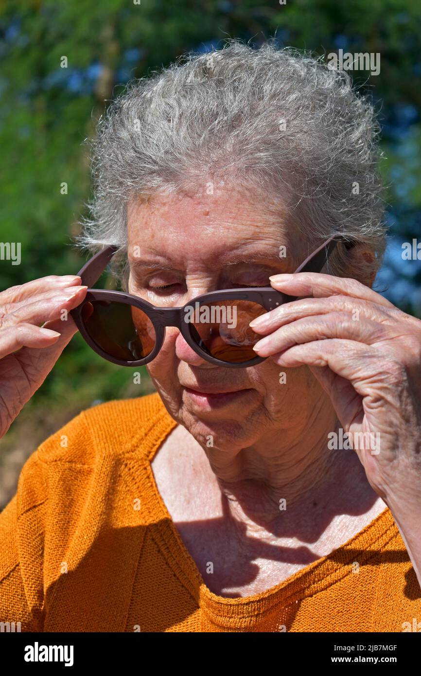 Elderly woman putting on sunglasses Stock Photo Alamy