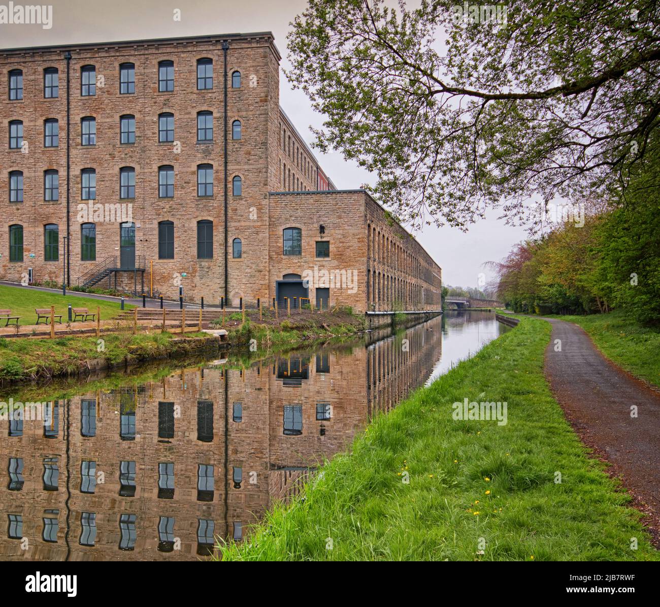 Reflections of Tunstill Mill in its renovated condition. The former Smith and Nephew textile mill stands by the Leeds and Liverpool Canal Stock Photo