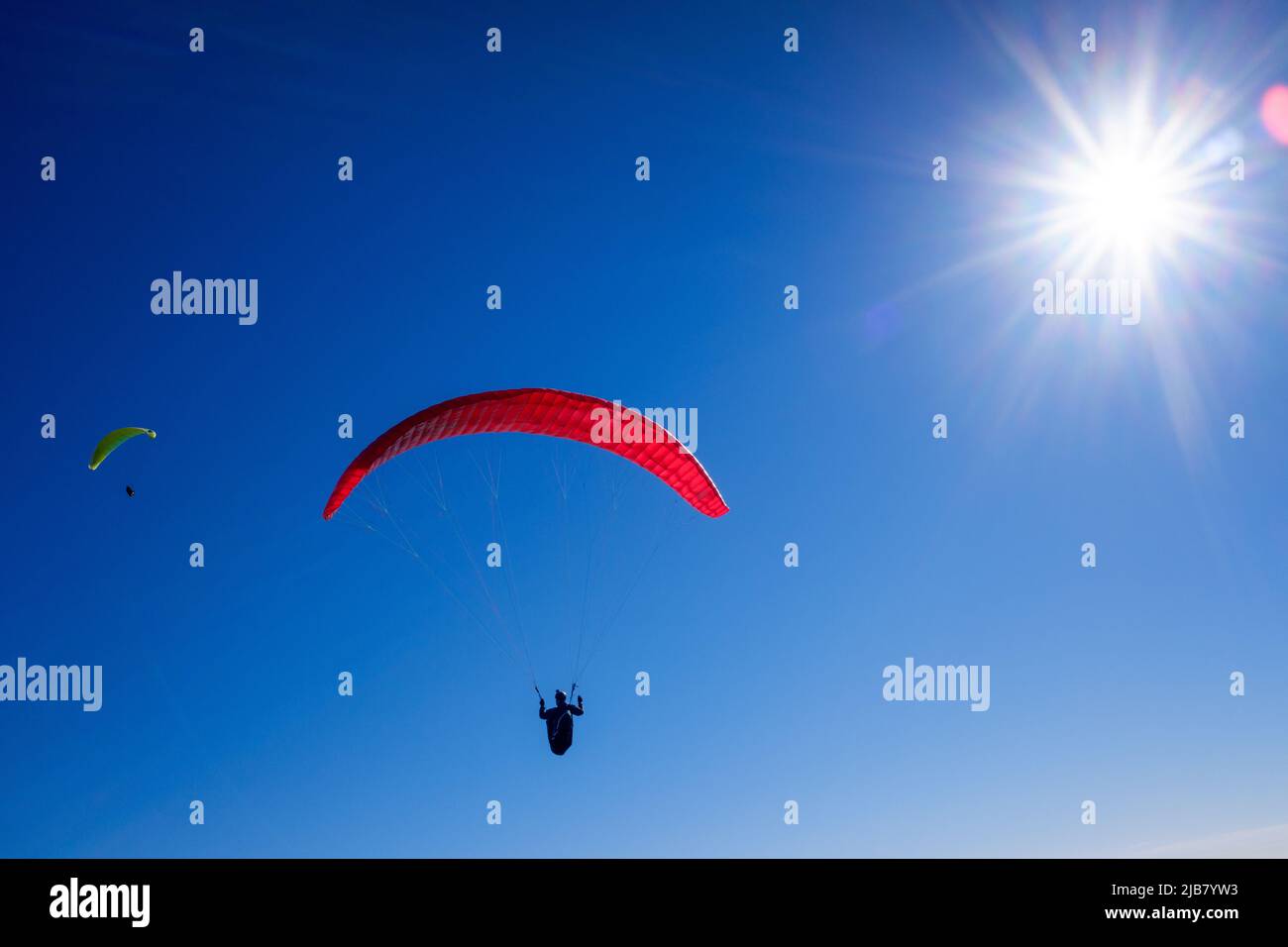Paragliders glide through the air by launching themselves from high mountains with special parachutes. Stock Photo
