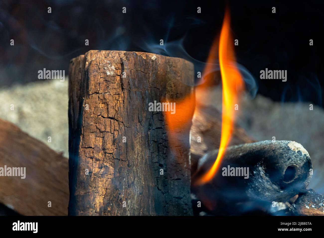 Mesquite dried-wood log emits a massive orange flame inside a large fire pit. Stock Photo