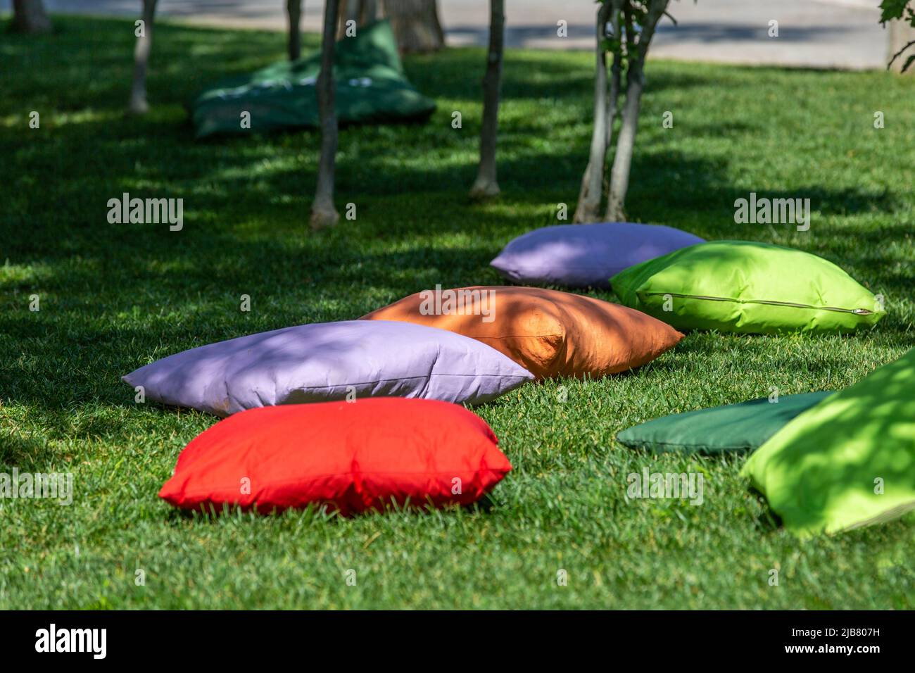 Students sitting on cushions under trees Stock Photo Alamy