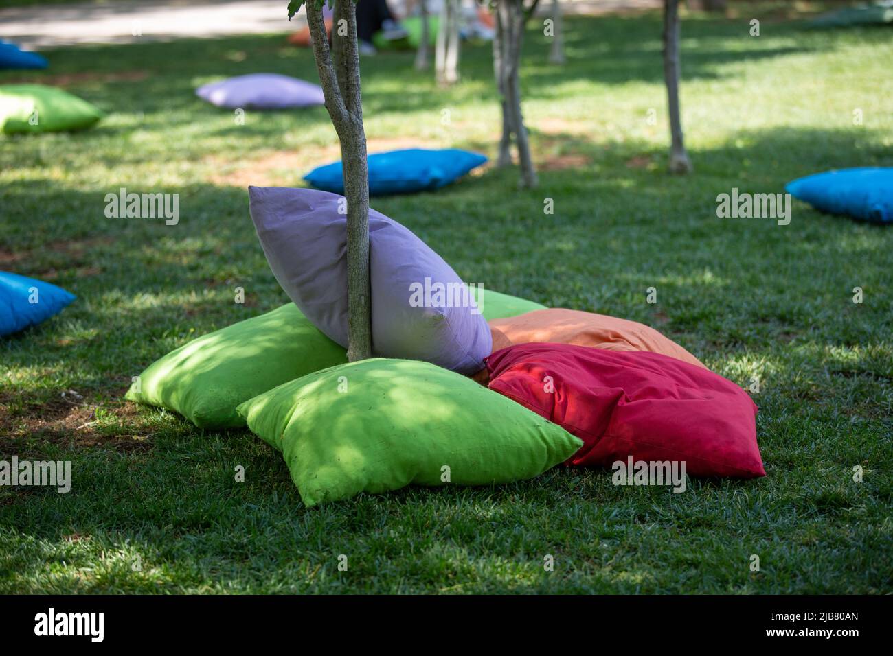 Students sitting on cushions under trees Stock Photo Alamy