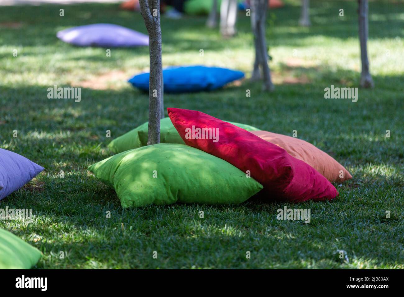 Students sitting on cushions under trees Stock Photo Alamy