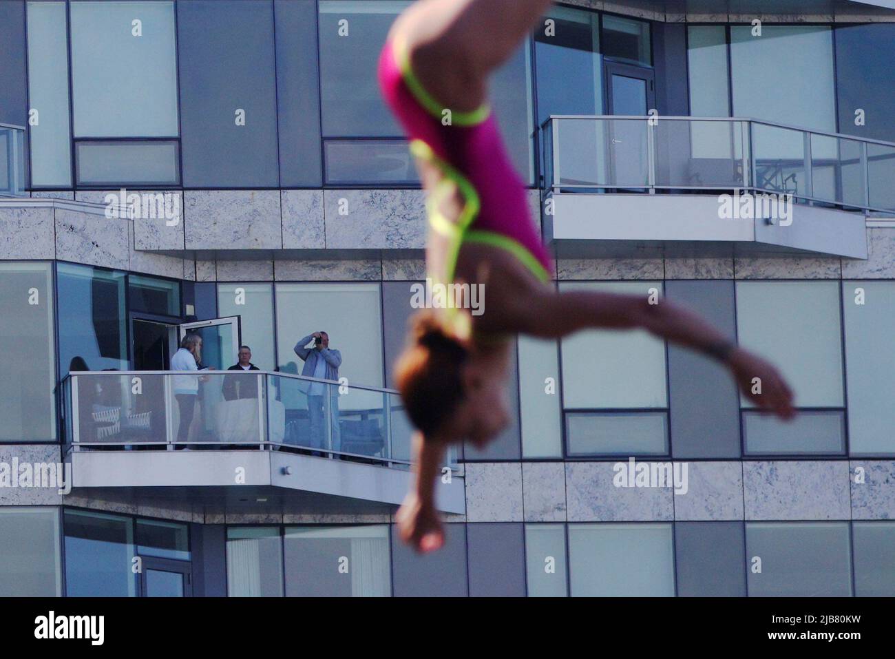 Spectators on the balcony of a residential building watch Antonina Vyshyvanova of Ukraine dive off the roof of the Institute of Contemporary Art while competing at the Red Bull Cliff Diving World Series in Boston, Massachusetts, U.S., June 3, 2022.   REUTERS/Brian Snyder TPX IMAGES OF THE DAY Stock Photo