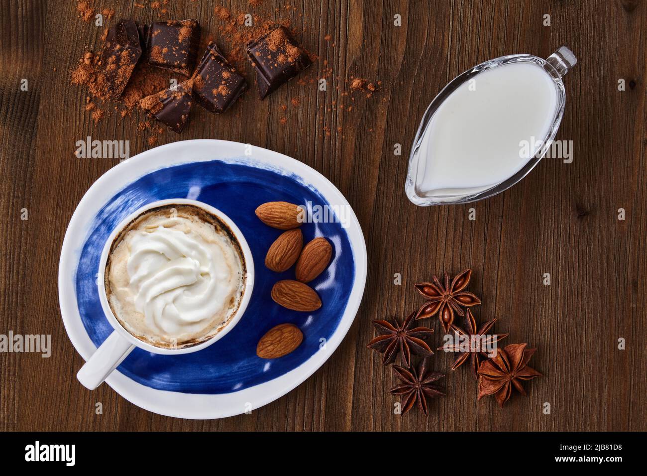 Blue cup of Viennese coffee with cream, chocolate and spices on a dark wooden table Stock Photo