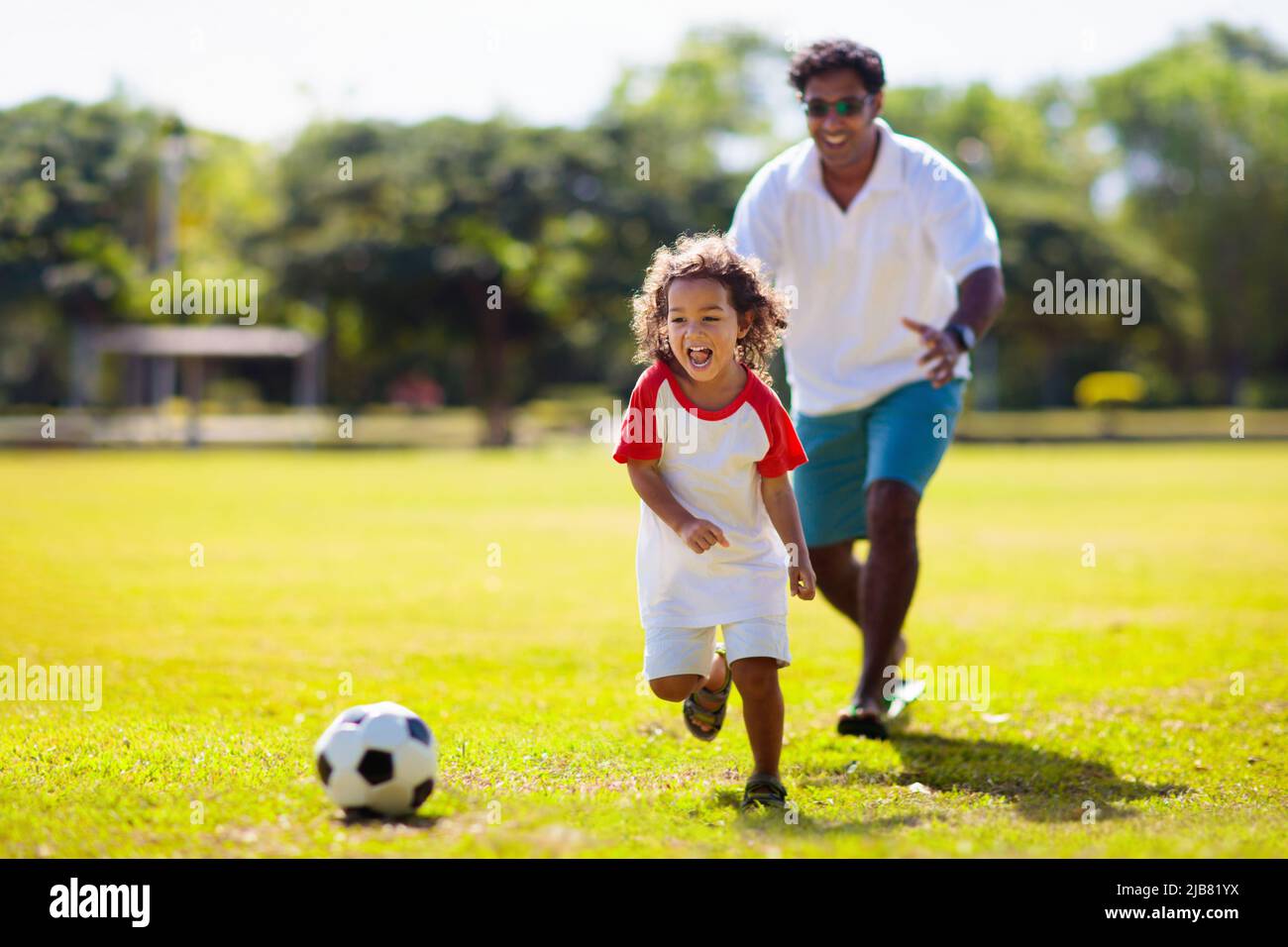 Father and son play football. Dad and little boy play soccer. Young