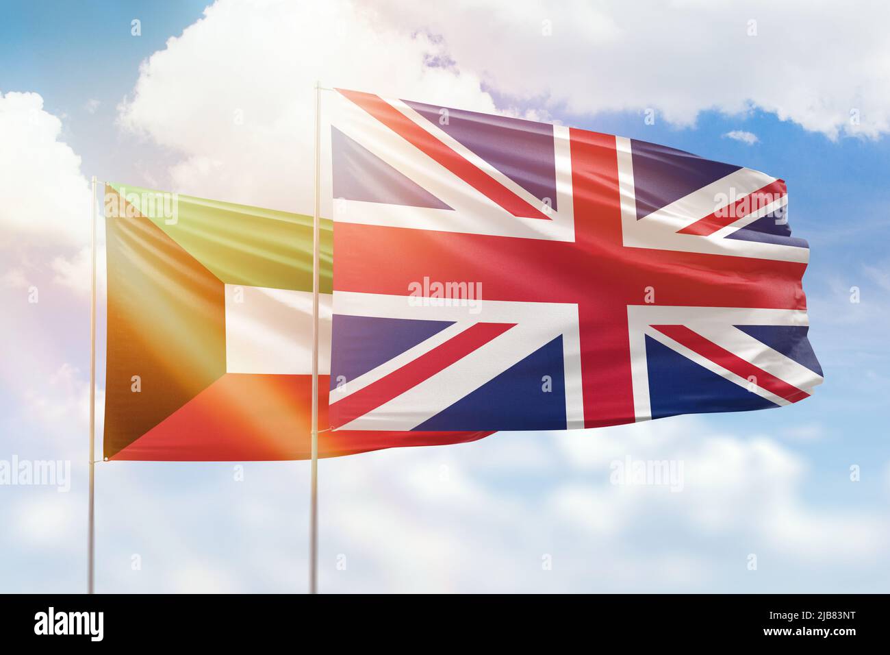 Sunny blue sky and flags of united kingdom and kuwait Stock Photo