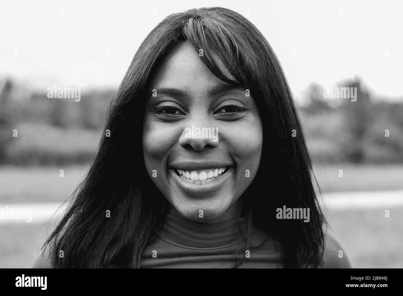 Happy hispanic young girl smiling on camera outdoor - Focus on face - Black and white editing Stock Photo