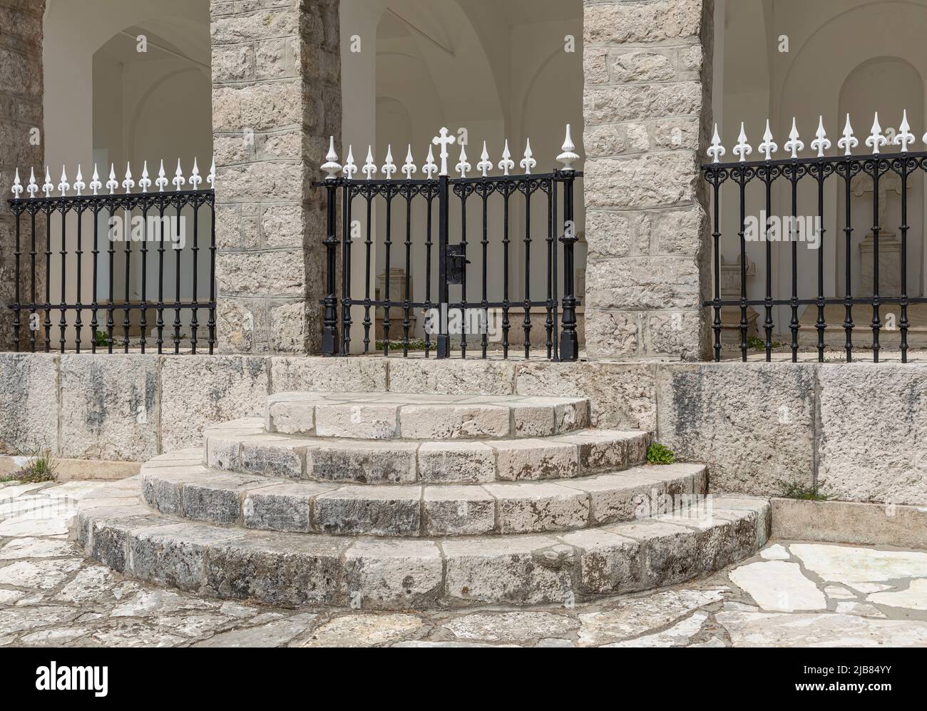 Circular steps leading up to a gate in black and white wrought iron
