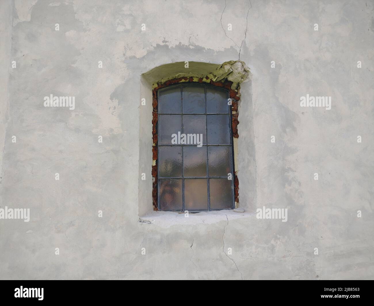 An old window in the gray wall of an church. Stock Photo