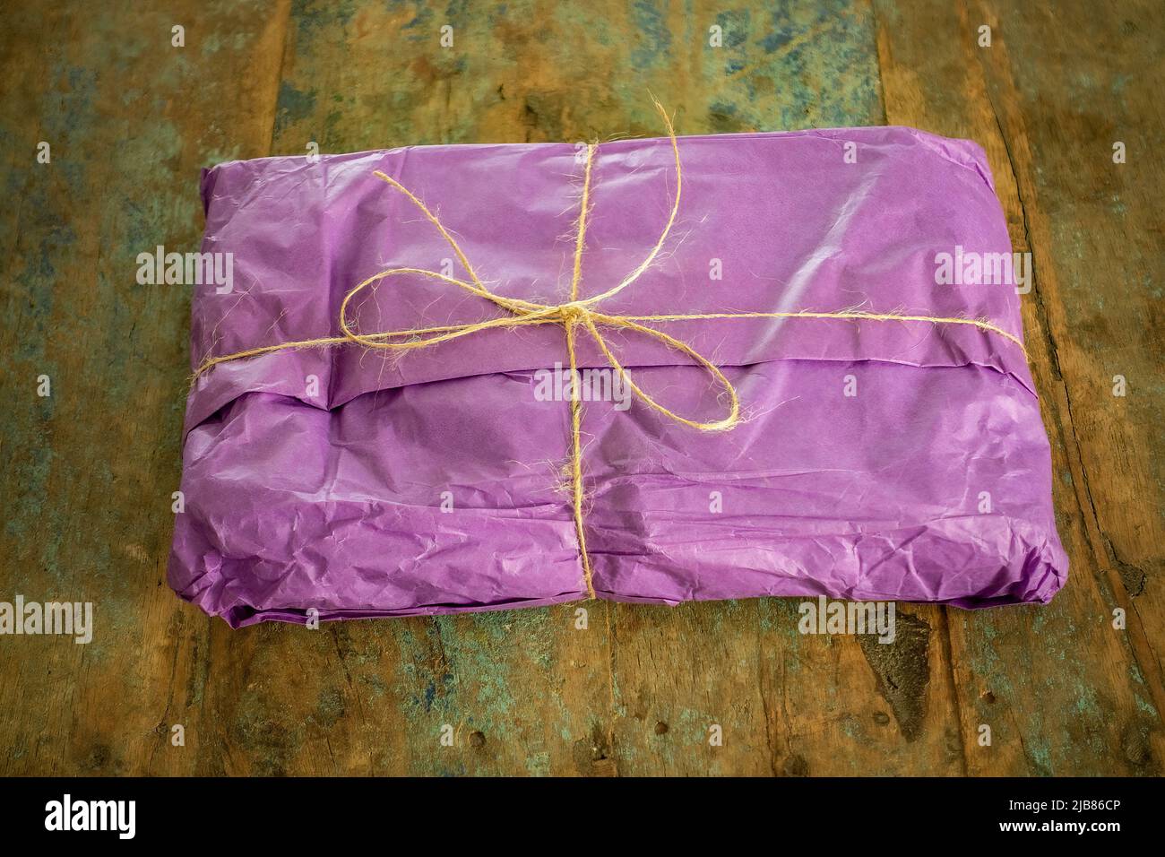 gift wrapped present, wrapped in purple tissue and with a string bow Stock Photo