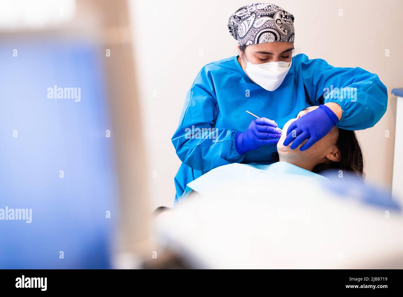 Female dentist doing a routine dental checkup using a mouth mirror and an excavator, to a female patient  Stock Photo