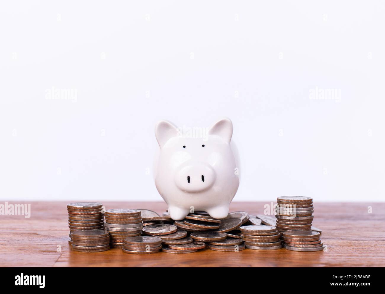 A piggy bank is placed on a pile of coins, Saving money for the happiness of life and goals in life. Money coins stack for growing growth with piggy b Stock Photo