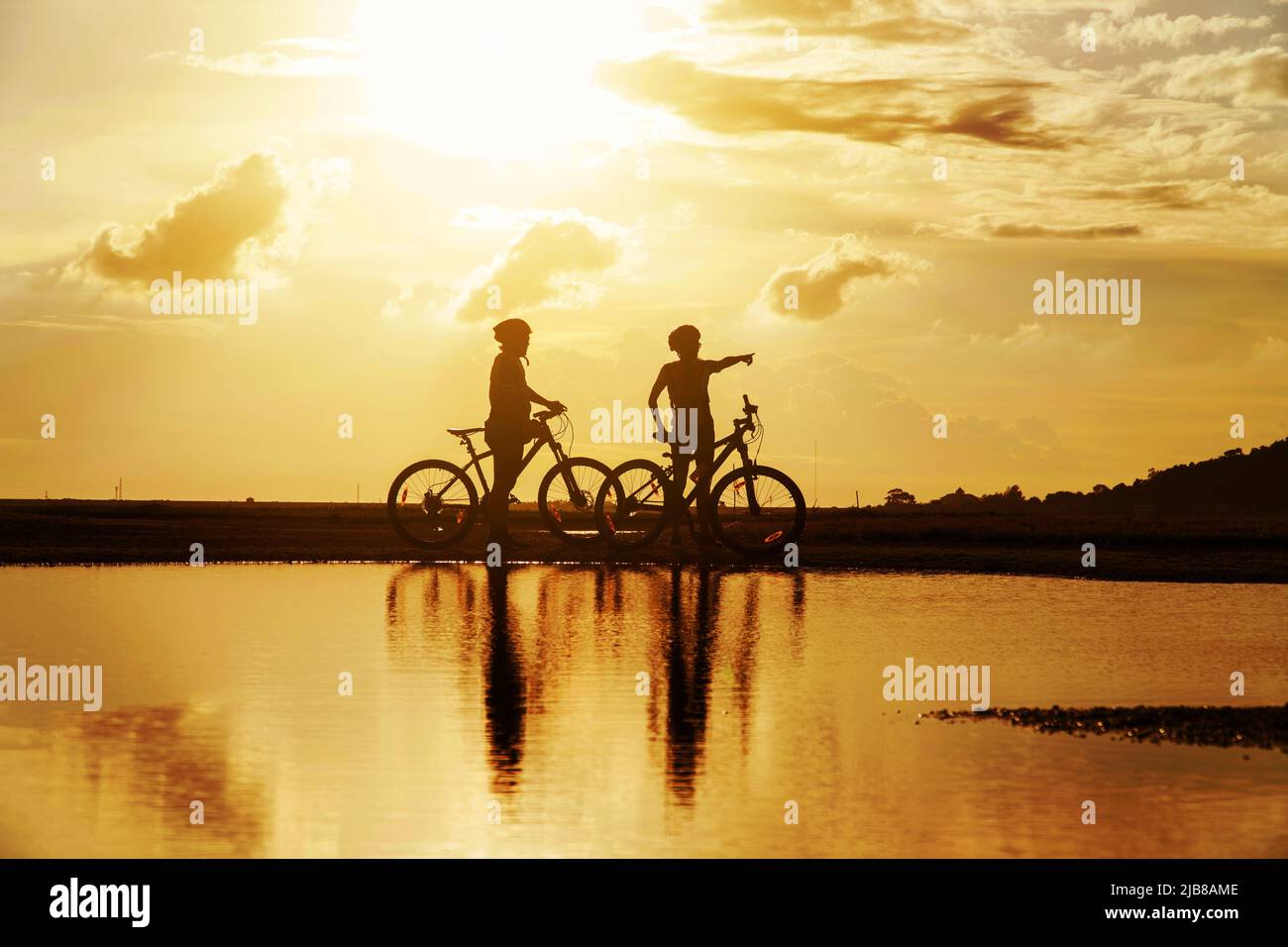 Young Couple in love fun and happy riding mountain bike after covid-19 coronavirus outbreak. End of the coronavirus outbreak. Silhouette cycling man a Stock Photo