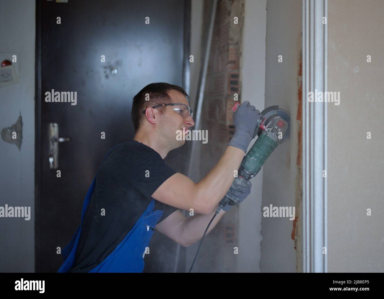 Handyman using machine to make a hole in a wall Stock Photo