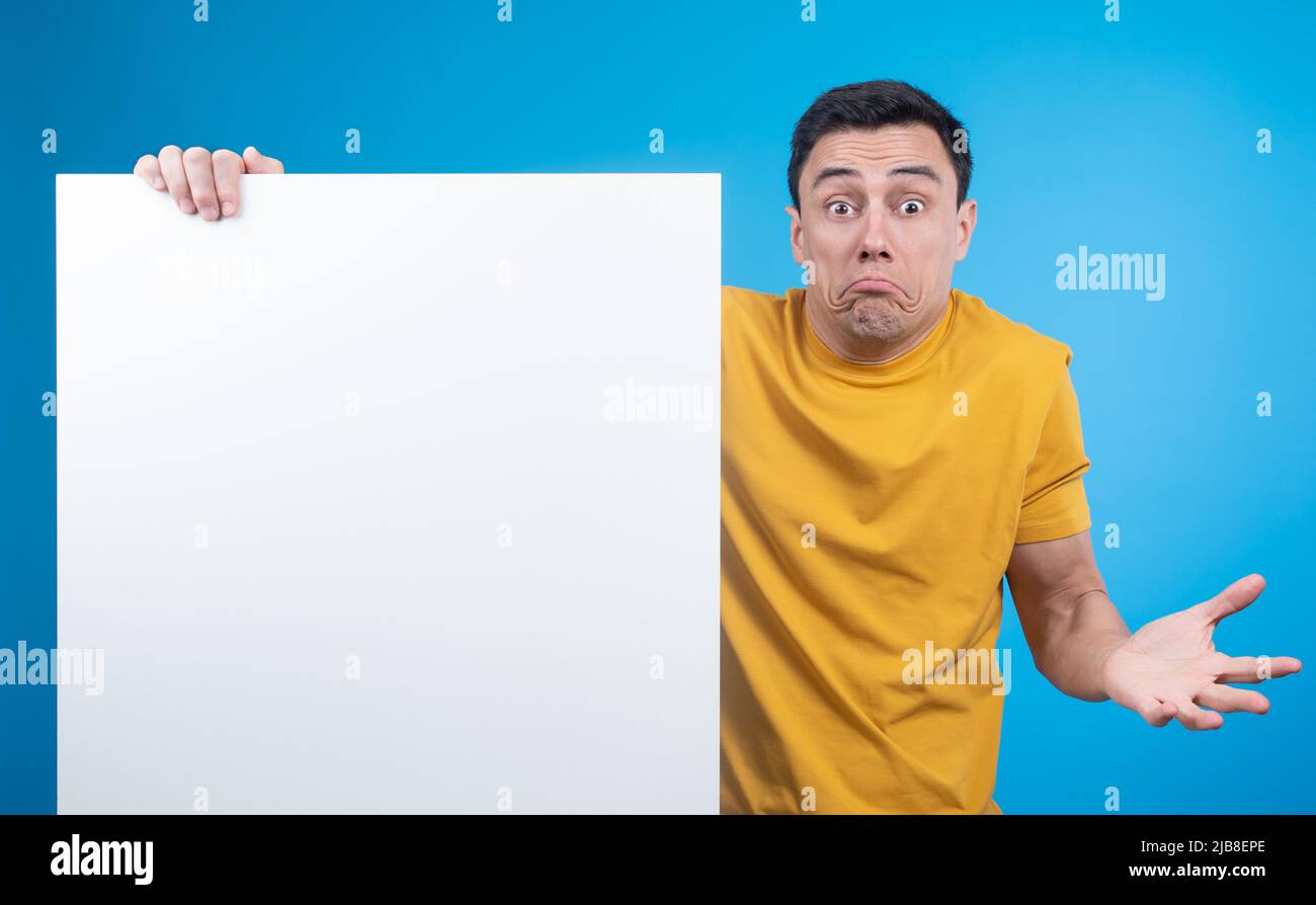 Unsure man shrugging shoulders and showing blank banner Stock Photo
