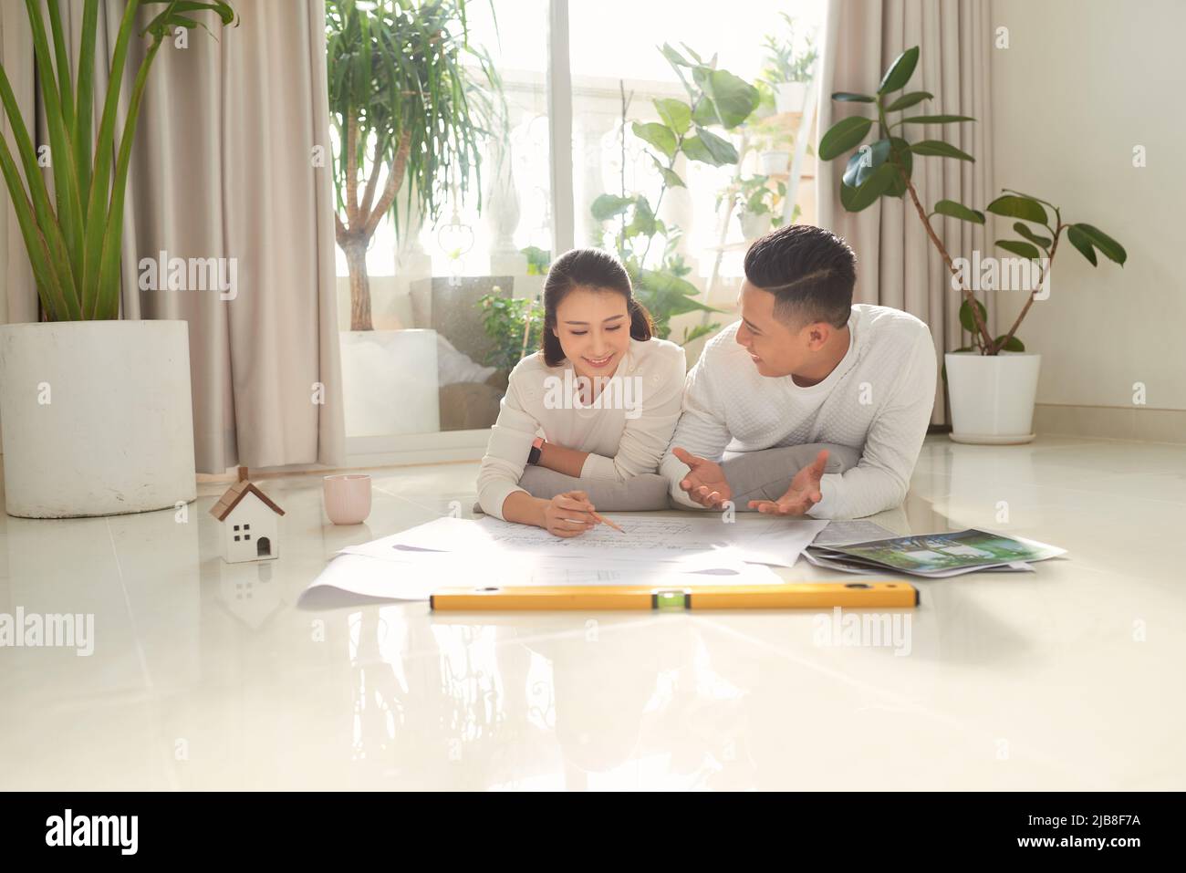 Young couple sitting on floor with apartment plan Stock Photo