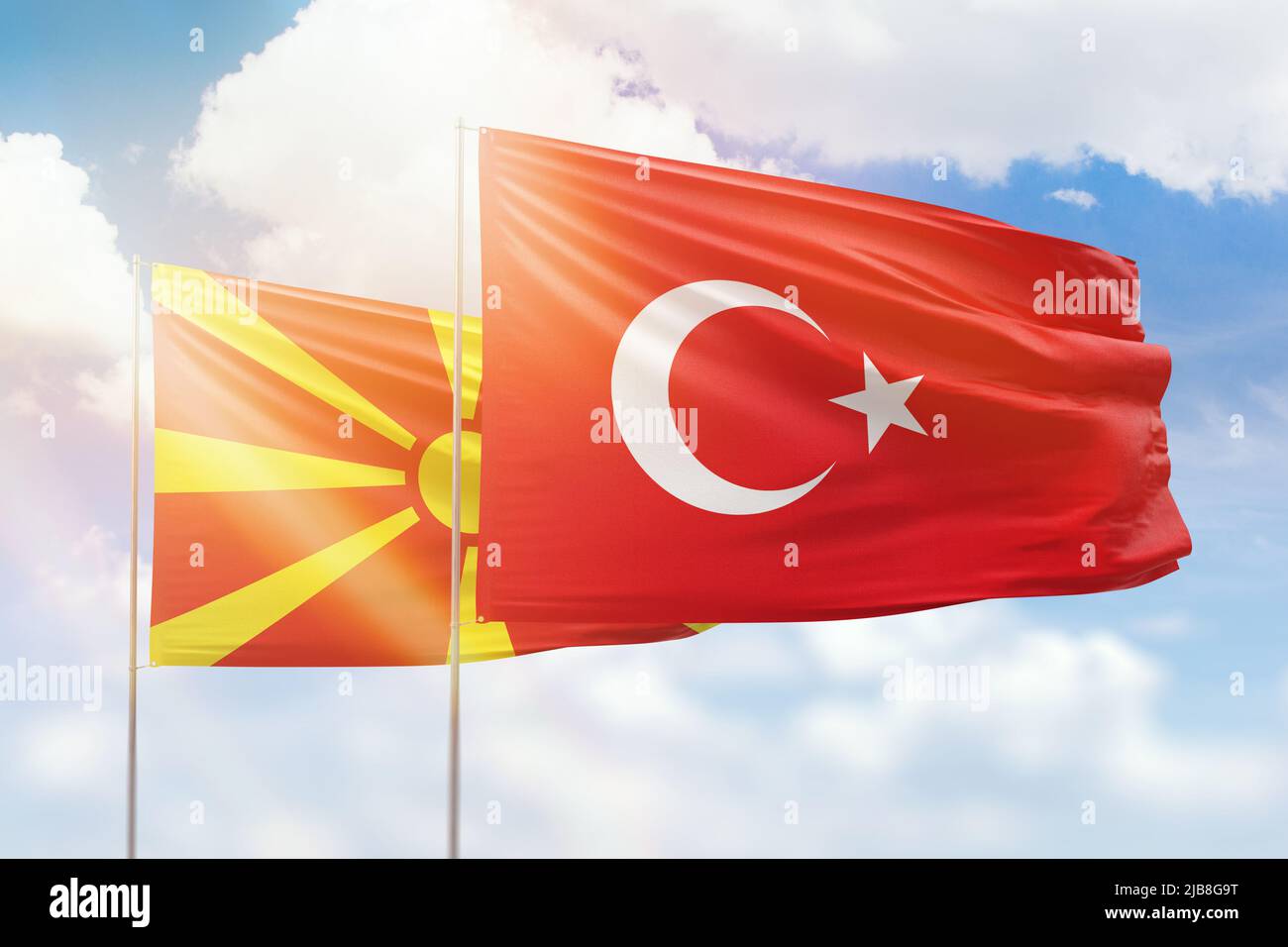 Sunny blue sky and flags of turkey and north macedonia Stock Photo
