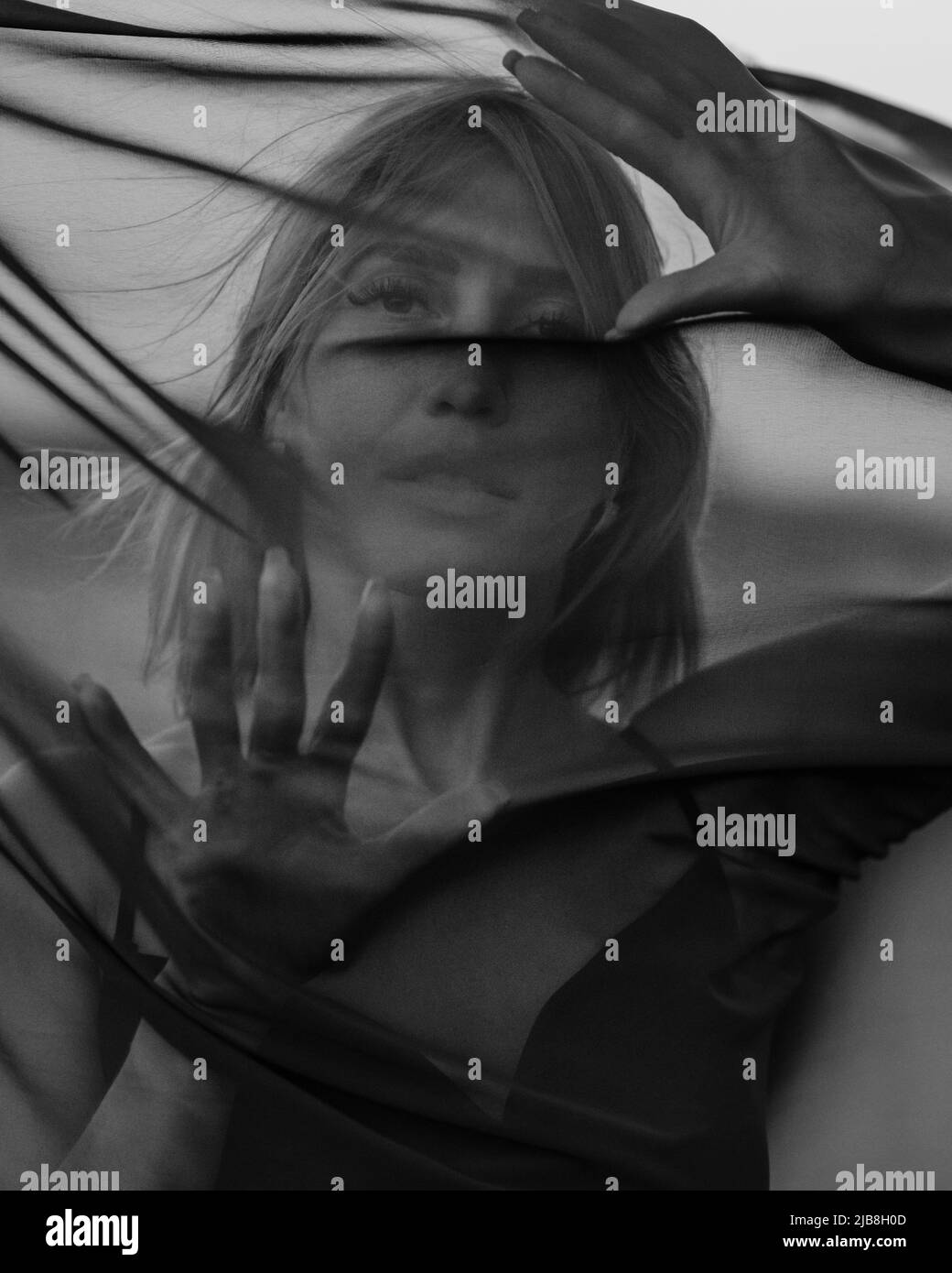 Portrait of woman under transparent textile. Black and white Stock Photo