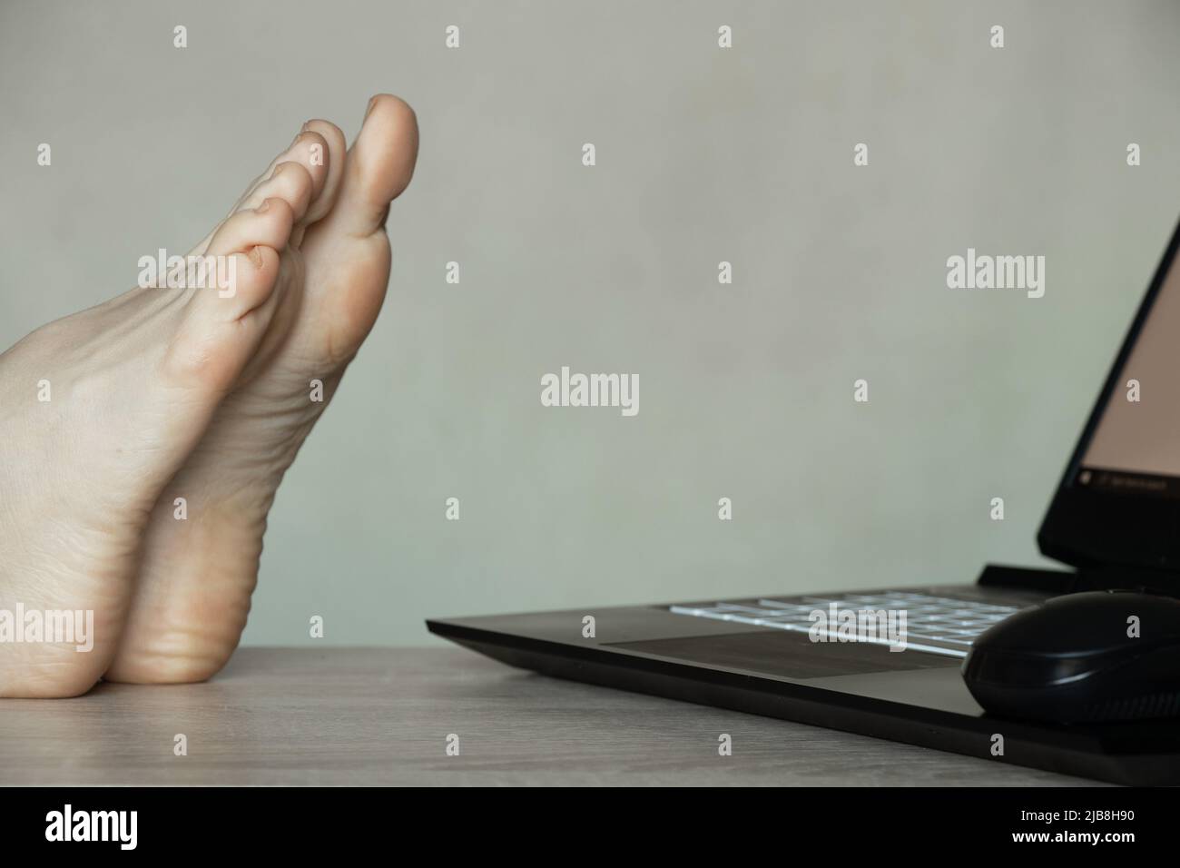 female legs on the desk near the laptop, rest at work, legs at the table, break Stock Photo