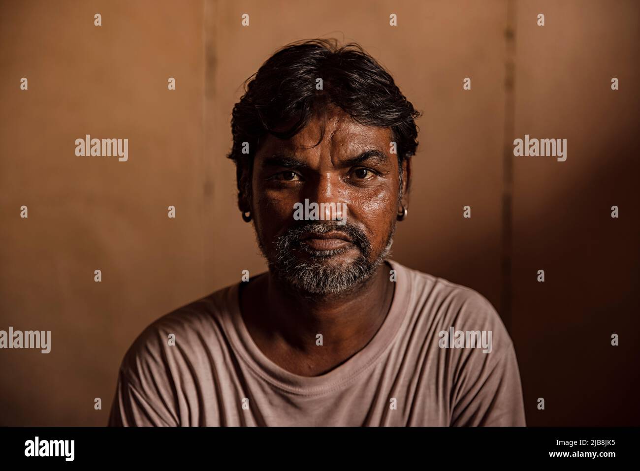 Portrait of a senior slum man sitting at home Stock Photo